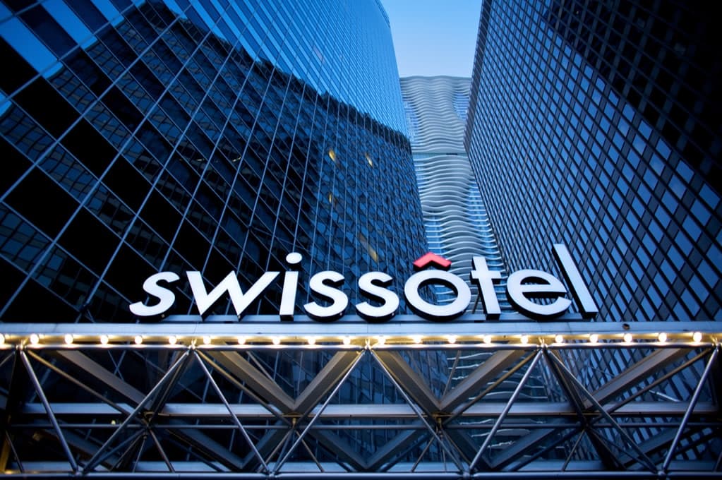 The triangular glass facade of Swissôtel Chicago reflecting the blue waters of the Chicago River and Lake Michigan under a clear sky.