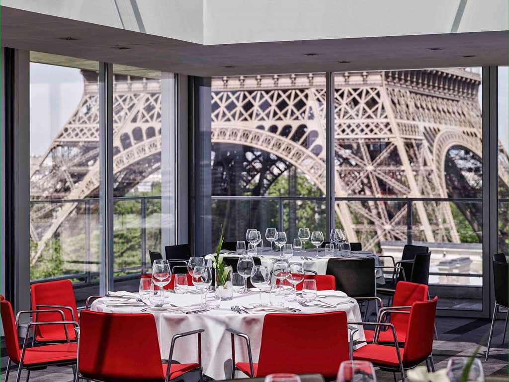 A guest enjoying breakfast on a private balcony at Pullman Paris Tour Eiffel with a close-up view of the Eiffel Tower.