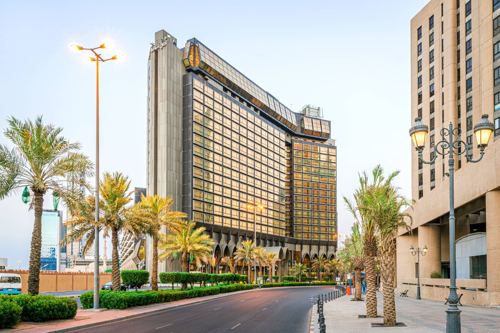 The renovated lobby lounge of JW Marriott Kuwait City featuring curved beige sofas, modern glass lighting, and floor-to-ceiling windows overlooking the city.