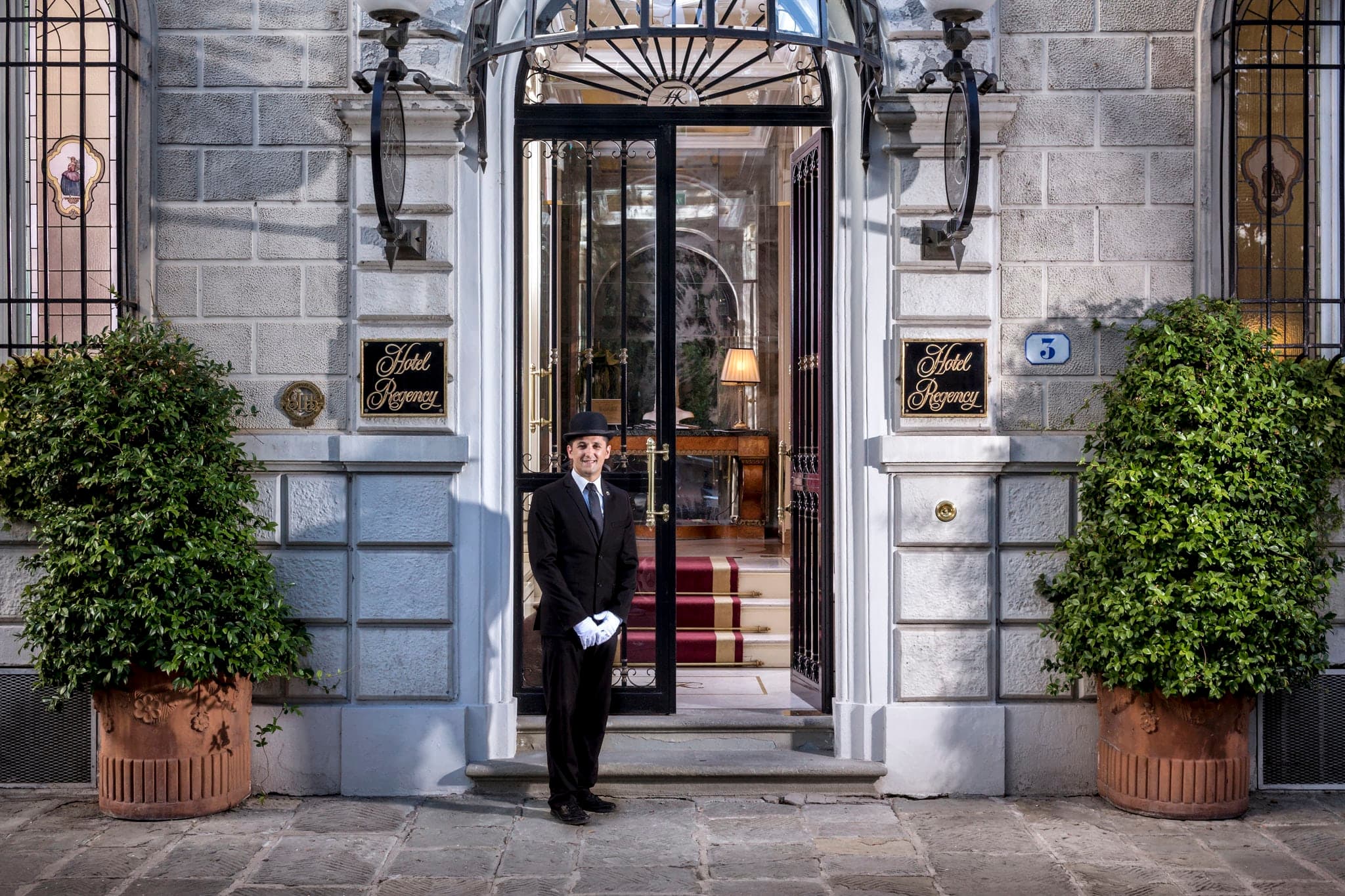 A lush, private courtyard garden at Hotel Regency Florence set for breakfast with white linens and silver, surrounded by ivy-covered walls.