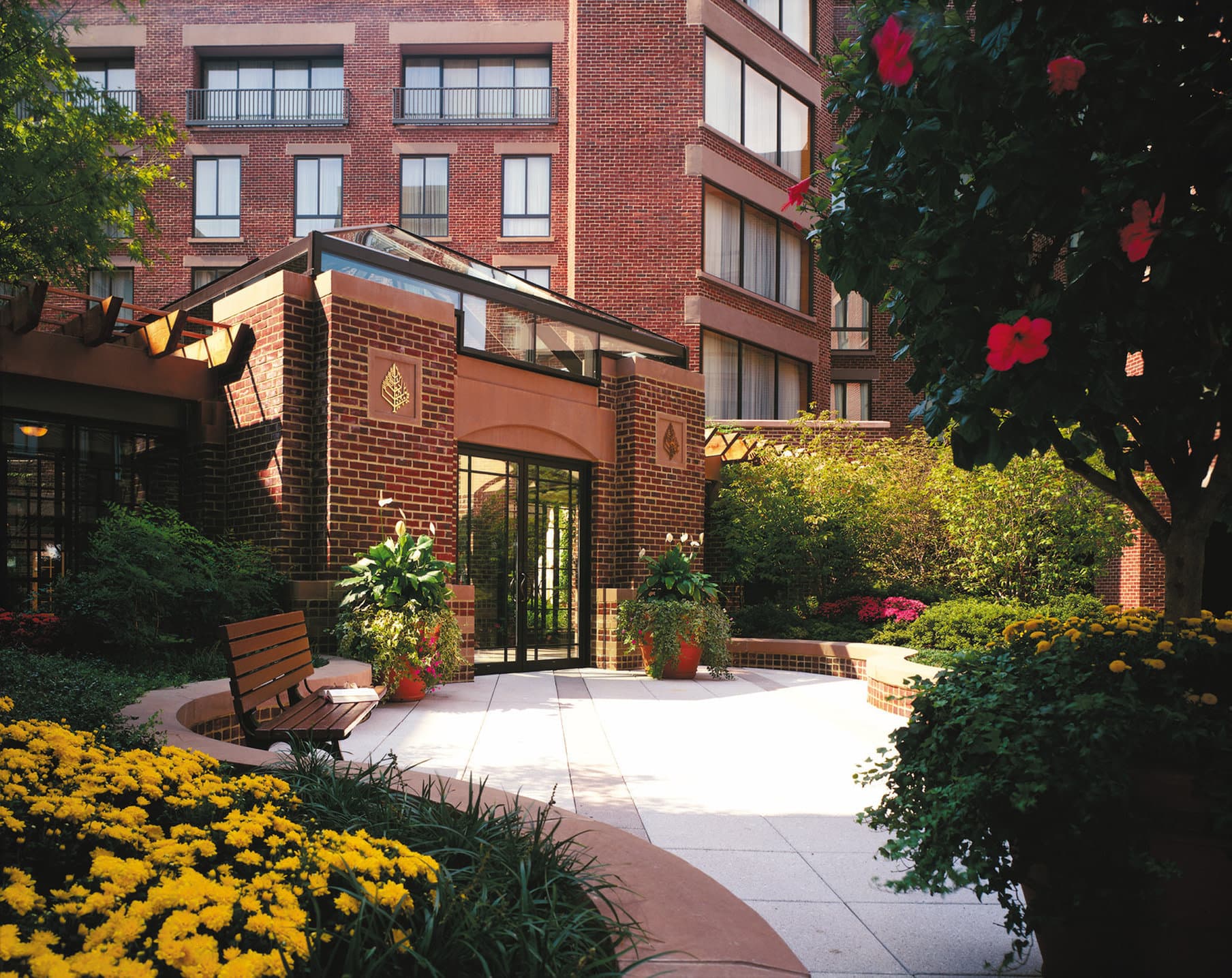 The glass-enclosed garden walkway at Four Seasons Washington DC filled with seasonal floral arrangements.