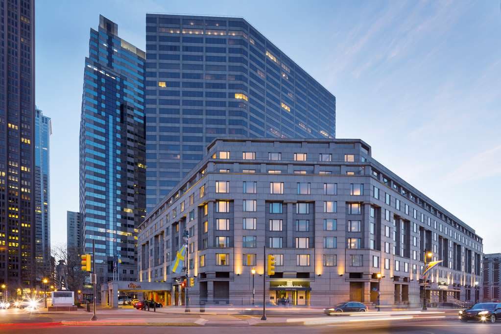 A sleek rooftop lounge at twilight with fire pits, glass railings, and a commanding view of the Benjamin Franklin Parkway and Philadelphia skyline.