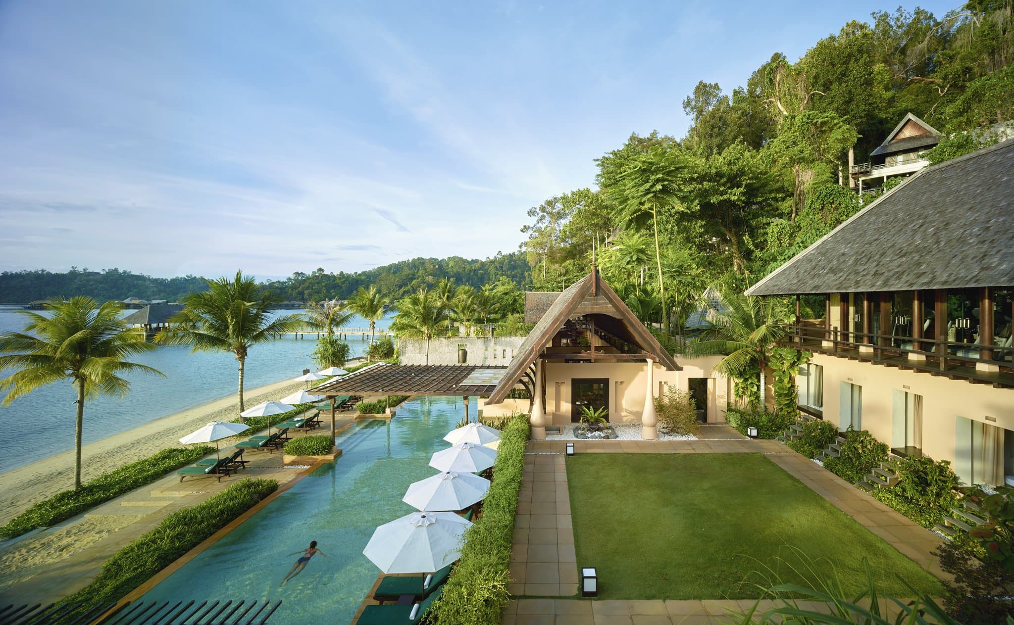 View from a hillside villa balcony at Gaya Island Resort looking out over the rainforest canopy towards the sea and Mount Kinabalu.