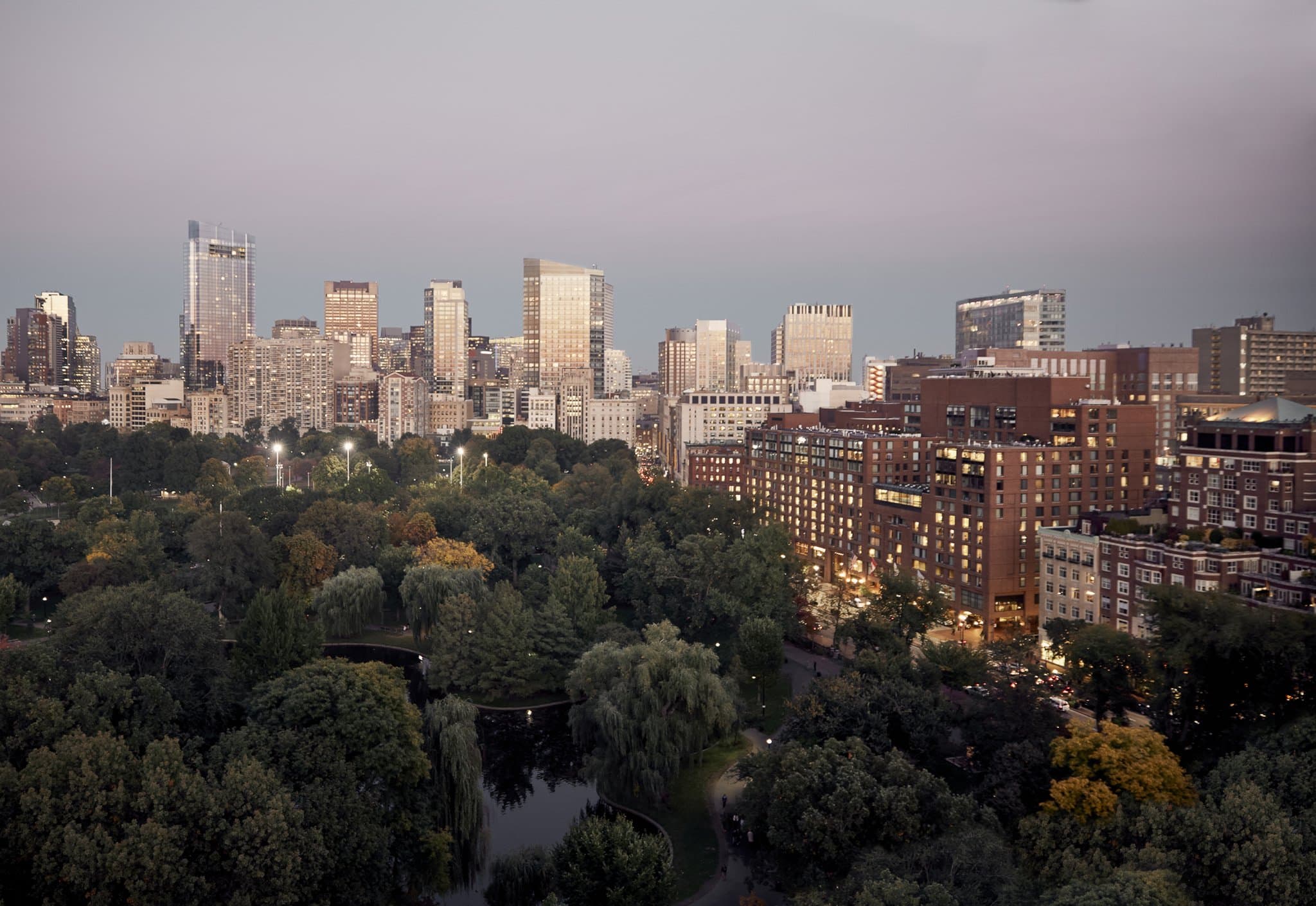 A serene view of the Four Seasons Boston indoor pool on the 8th floor with floor-to-ceiling windows overlooking the Public Garden autumn foliage.