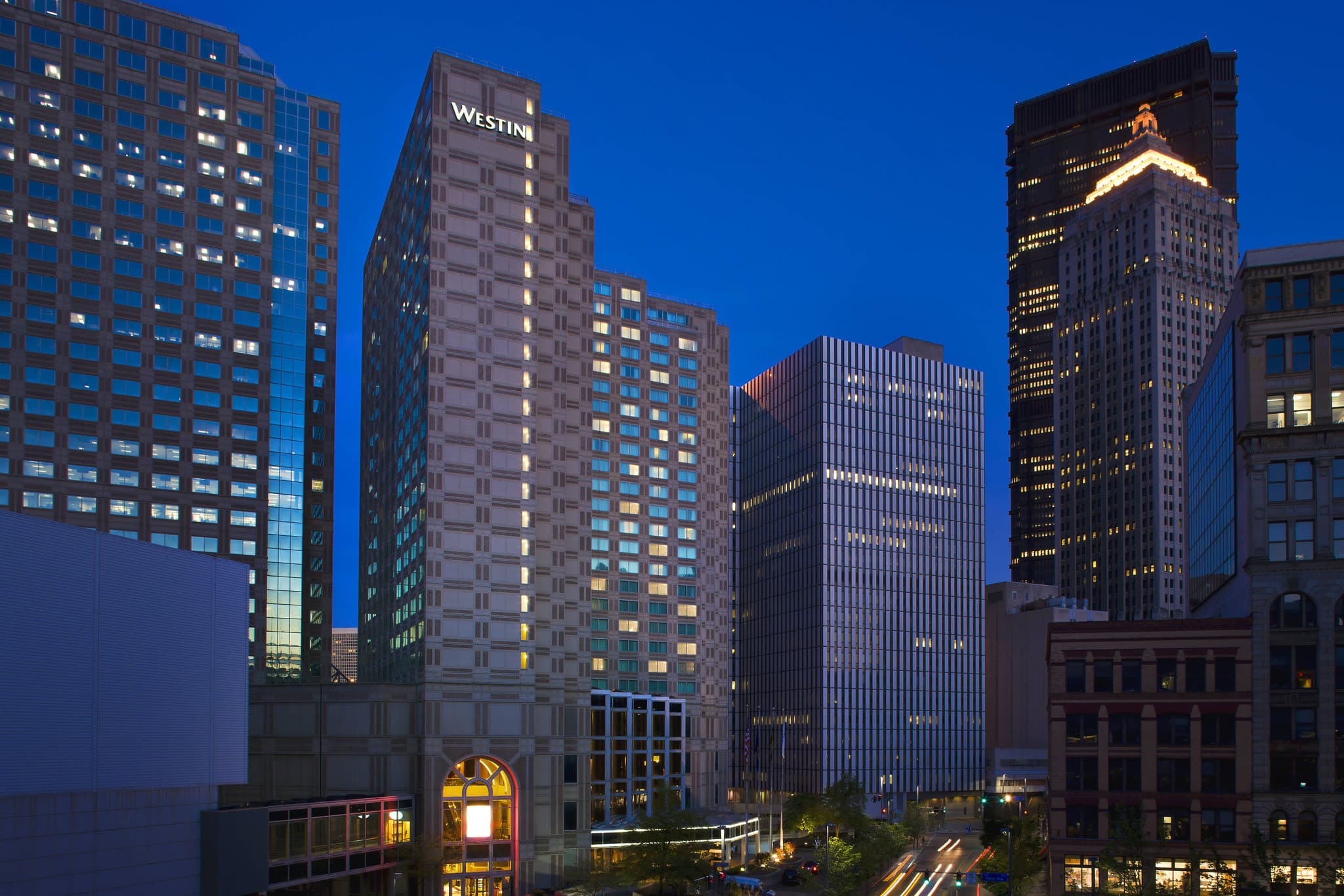 A dramatic low-angle shot of the glass skywalk connecting The Westin Pittsburgh to the convention center, reflecting the city skyline.