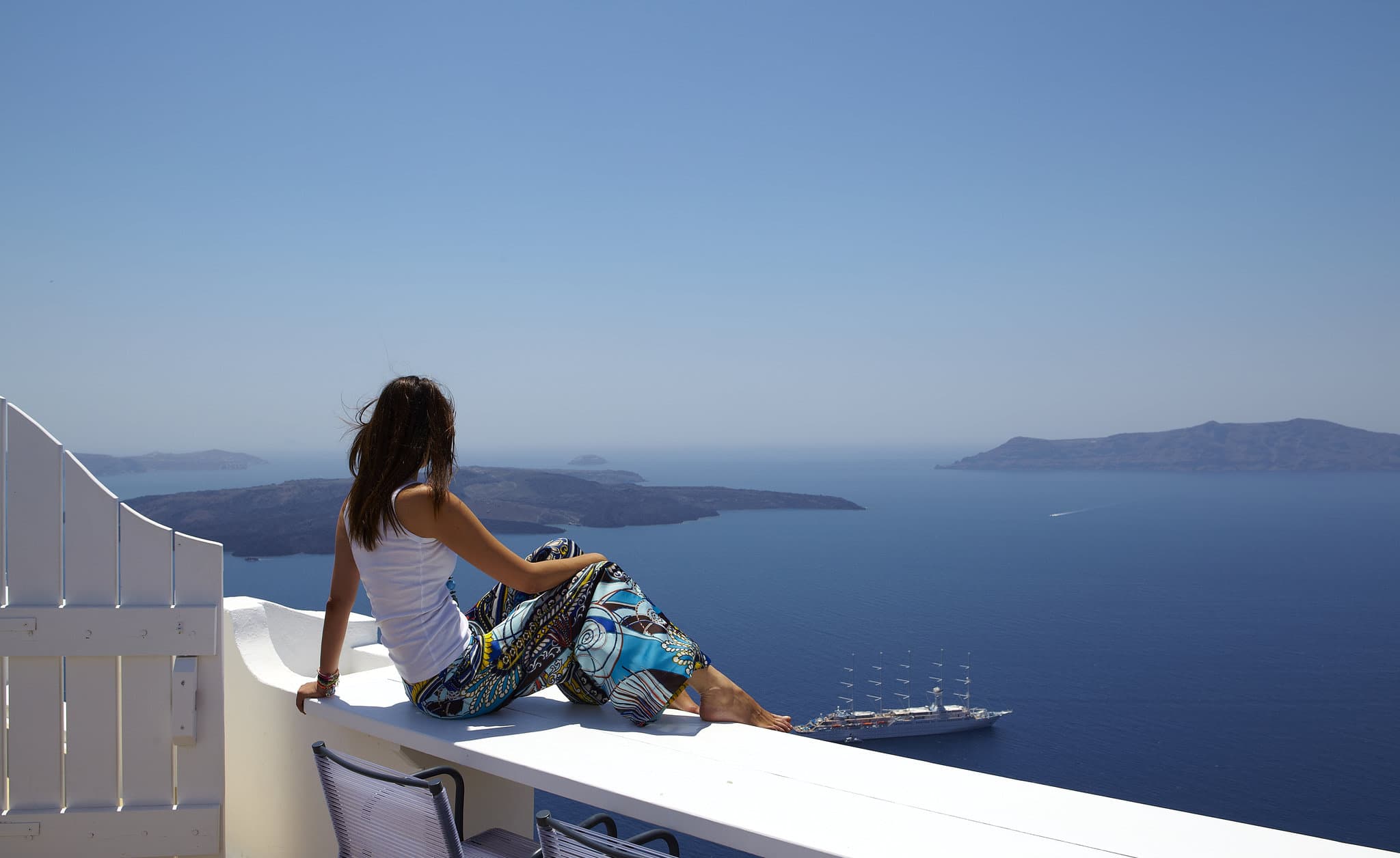 Sun Rocks Hotel Santorini infinity pool overlooking the volcanic caldera at sunset with white cliffside architecture.