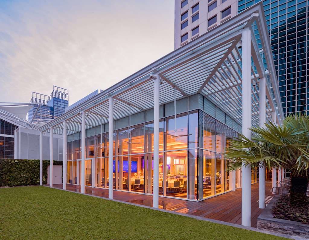A plush window-side daybed in a Conrad Centennial room overlooking the illuminated Fountain of Wealth at night.