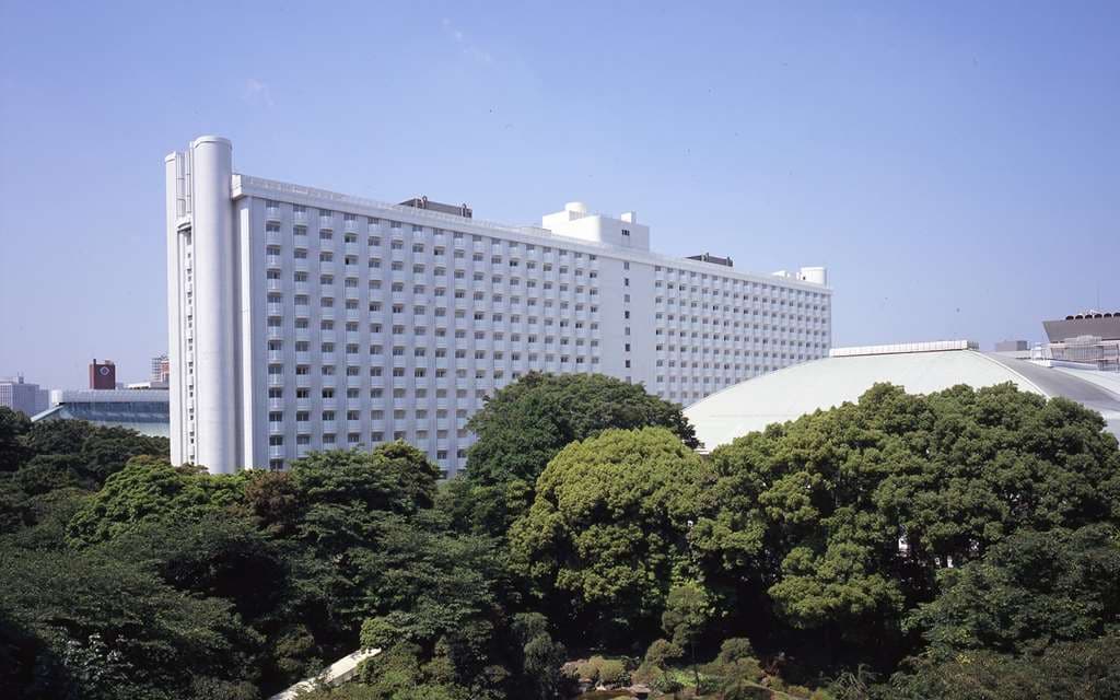 View from a balcony at Grand Prince Hotel Shin Takanawa looking out over the illuminated 20,000 sqm Japanese garden and Tokyo skyline.