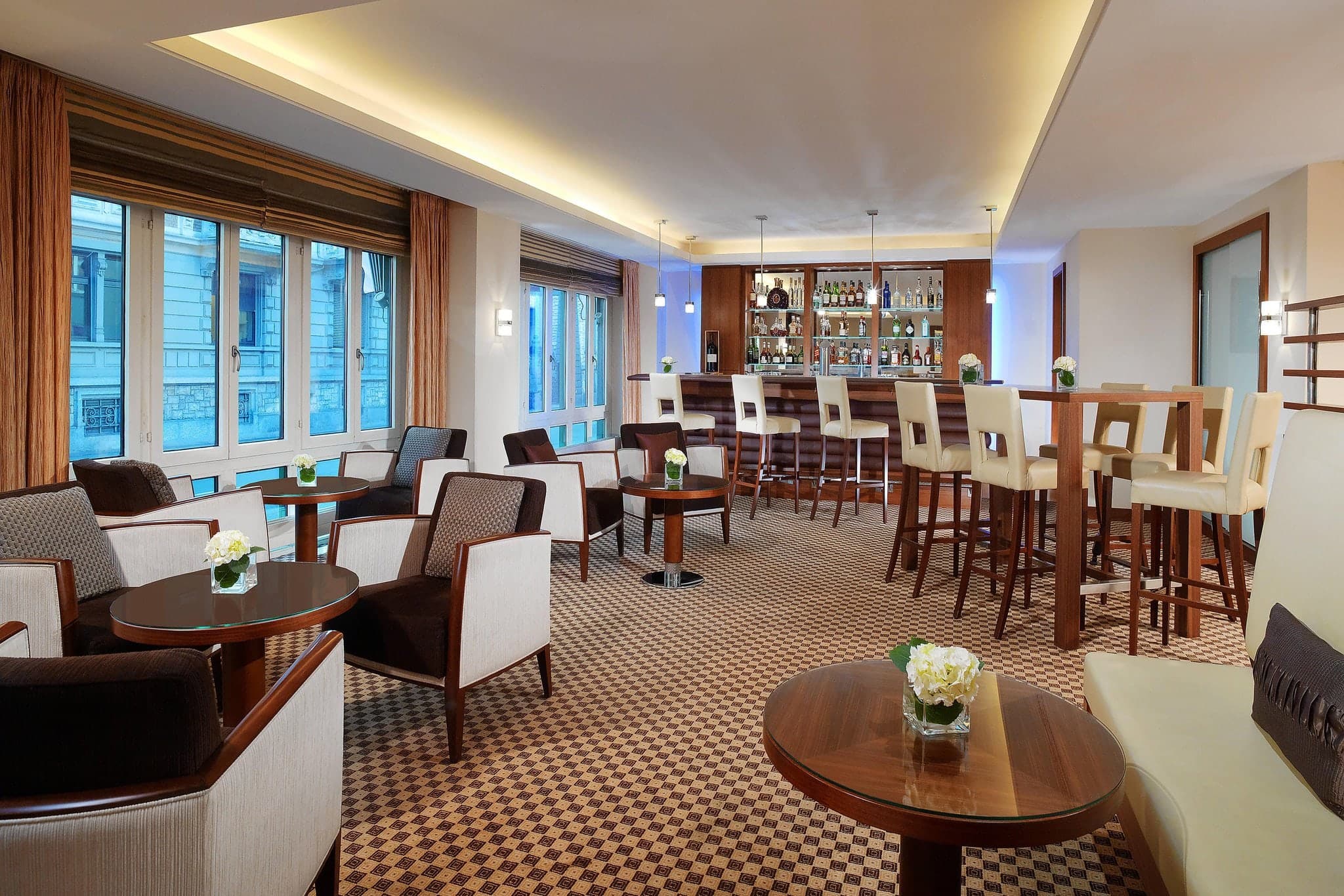 Lobby of Neues Schloss Privat Hotel Zurich featuring 1930s Art Deco elements, dark wood paneling, and modern Stellar Works furniture.