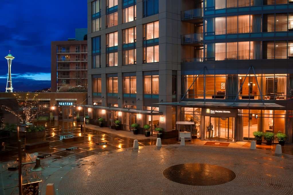 A sleek, modern hotel suite at Pan Pacific Seattle featuring floor-to-ceiling windows with a direct view of the Space Needle and a deep soaking tub.