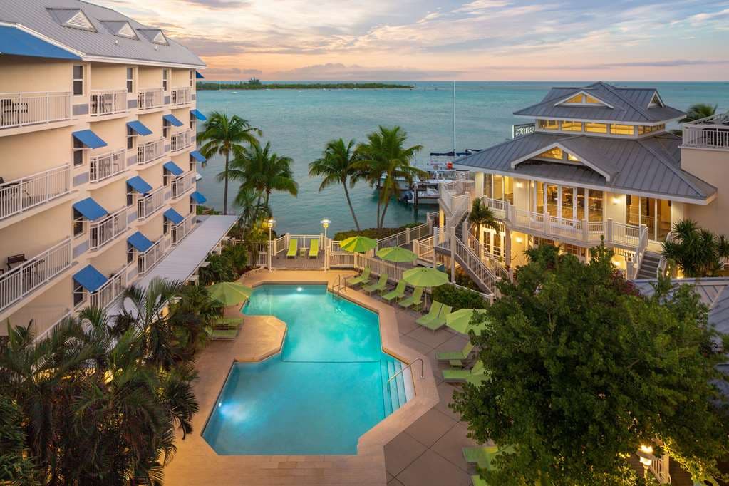 A couple enjoying cocktails on a private balcony at Hyatt Centric Key West overlooking the Gulf of Mexico at sunset.