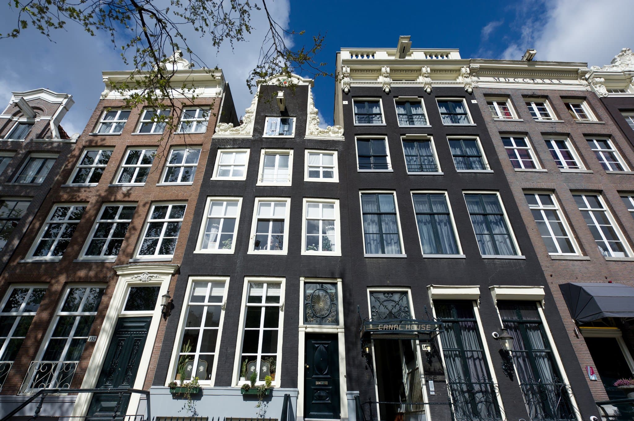 The Great Room at Canal House Amsterdam featuring dark walls, ornate chandeliers, and a view into the lush private garden.