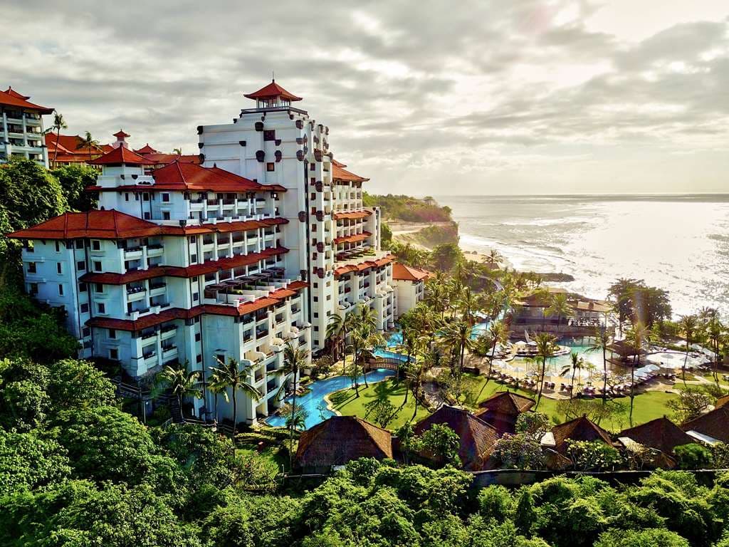 View from the Hilton Bali Resort Cliff Tower balcony looking down at the four lagoon pools and the Indian Ocean coastline.