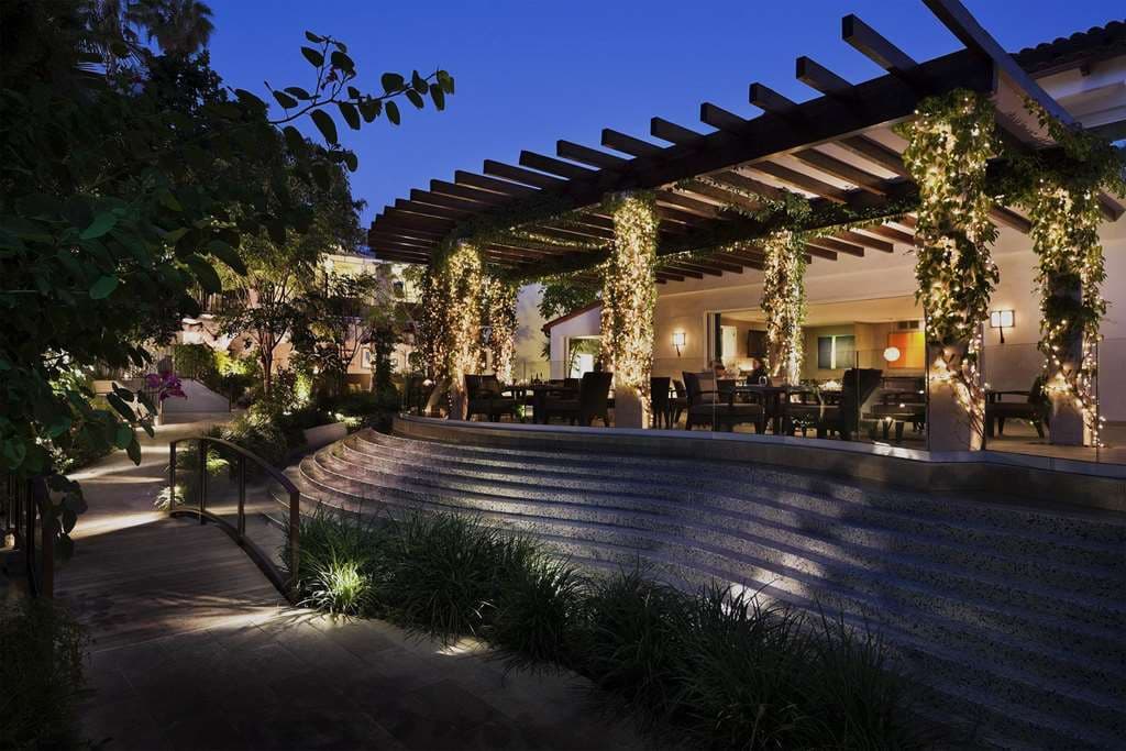 日落侯爵酒店內鬱鬱蔥蔥的私人庭院,一座木橋橫跨錦鯉池,周圍環繞著熱帶綠色植物。