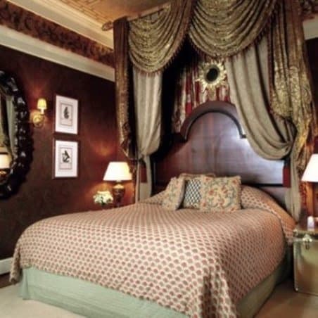 Opulent dining room at The Inn at Little Washington featuring maximalist decor, silk lampshades, and floral carpets.