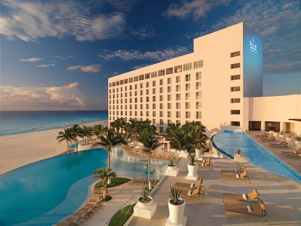 Le Blanc Spa Resort Cancun infinity pool at sunrise, overlooking the turquoise Caribbean sea with white architecture.
