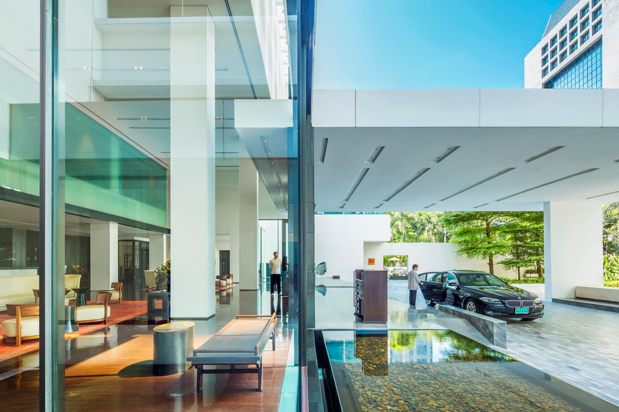 The iconic 25-meter outdoor lap pool at COMO Metropolitan Bangkok, flanked by white loungers and lush greenery.