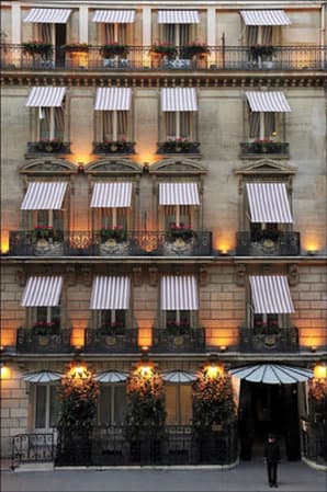 Hotel Lancaster Paris courtyard garden with red iron chairs and ivy-covered walls.