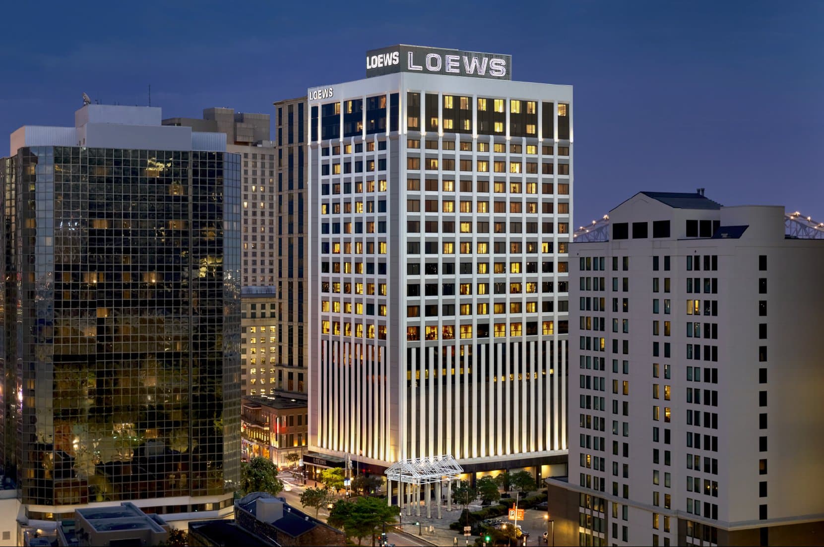 Loews New Orleans 宽敞的角房大床房,配有舒适的床铺和可俯瞰密西西比河的落地窗。