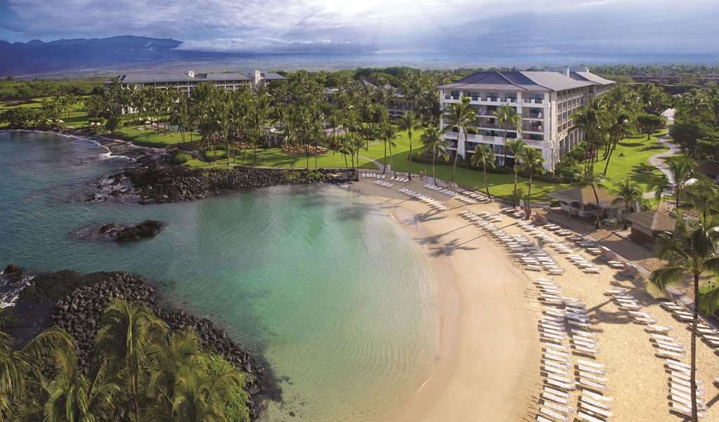 Fairmont Orchid Hawaii oceanfront lagoon pool at sunset with palm trees and torch lights.