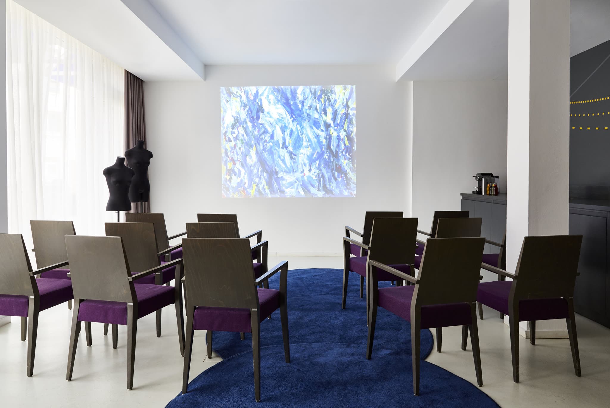 A stylized hotel room featuring a floor-to-ceiling Armin Morbach fashion mural behind a plush white bed.