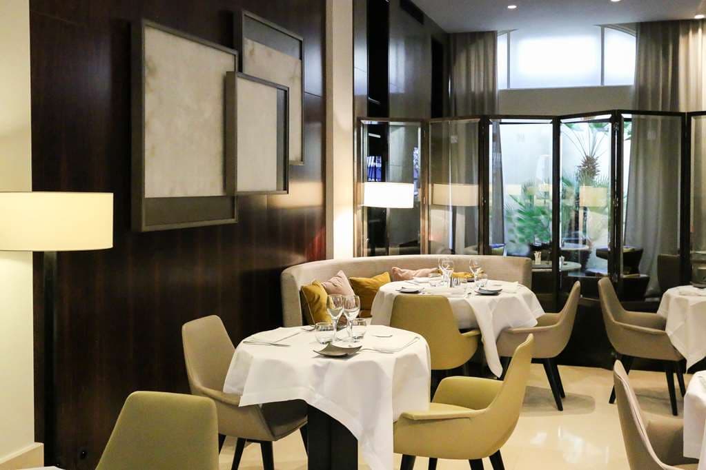 Hotel Montalembert的图书馆休息室,配有大理石壁炉、天鹅绒扶手椅和装满艺术书籍的落地书架。