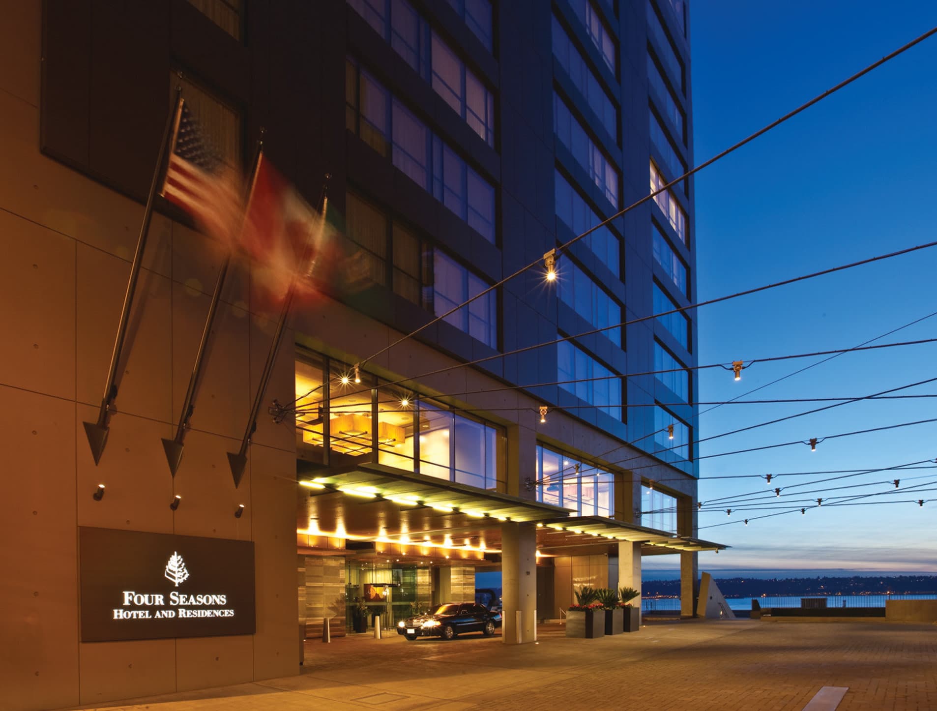 A heated outdoor infinity pool at Four Seasons Seattle overlooking the Great Wheel and Elliott Bay with ferries in the distance.
