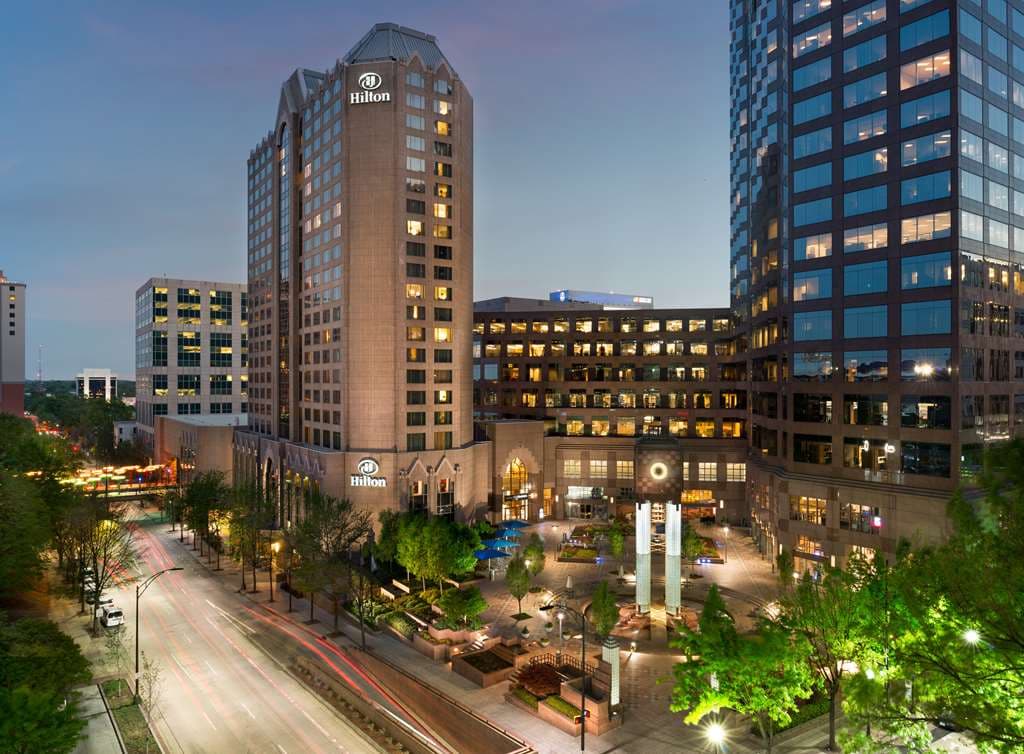 A dramatic view of the Hilton Charlotte Uptown's Plaza Atrium featuring a skylight and corporate-chic architectural details.