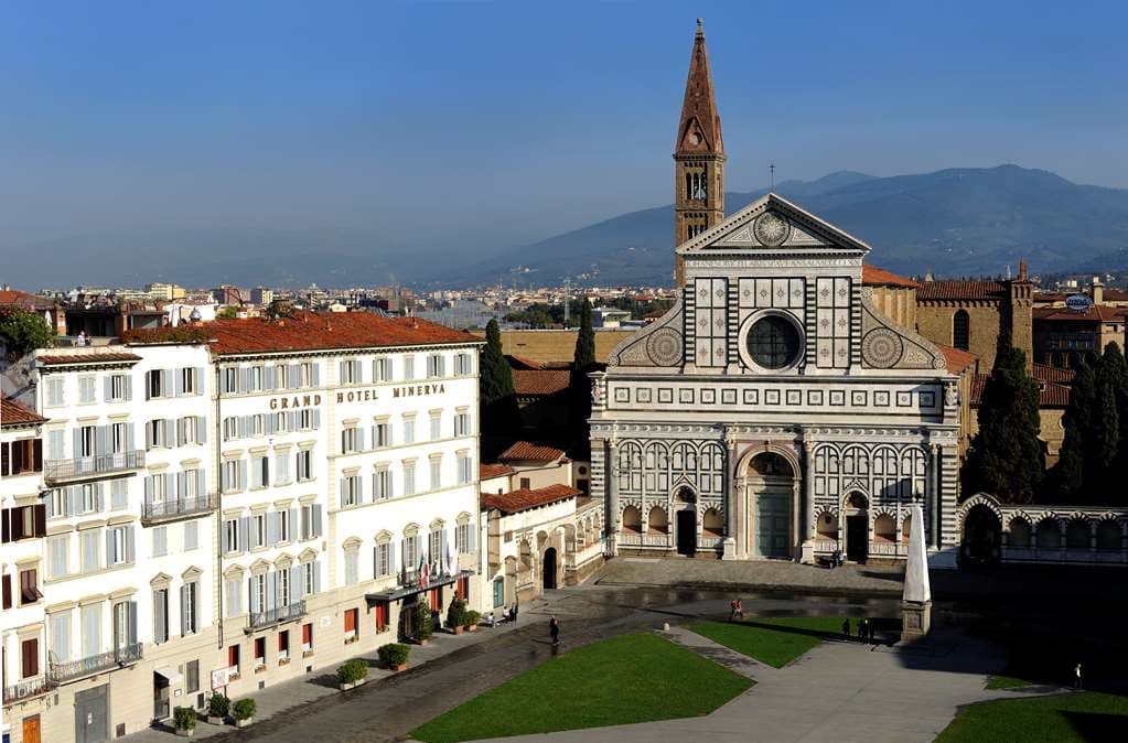 A swimmer in the Grand Hotel Minerva rooftop pool looking out at the Florence Duomo and Giotto's Bell Tower.