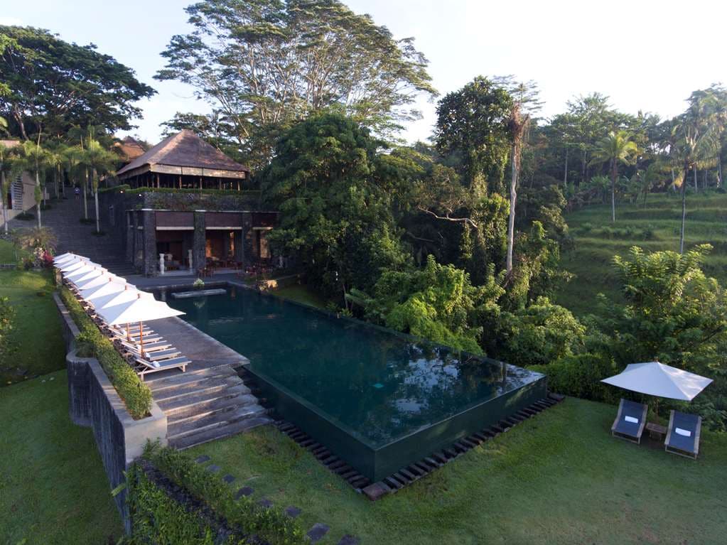 The iconic rectangular emerald infinity pool at Alila Ubud extending dramatically over the lush Ayung River valley jungle.