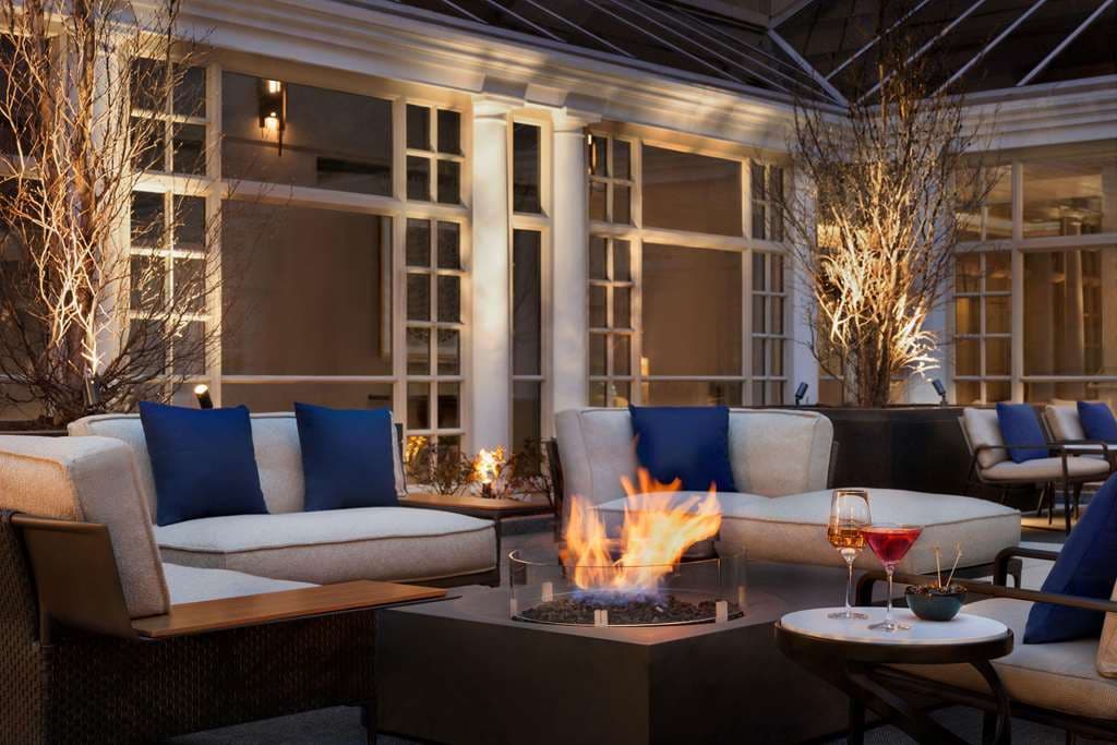 Fairmont Georgetown open-air courtyard garden with guests dining under cherry blossom trees.