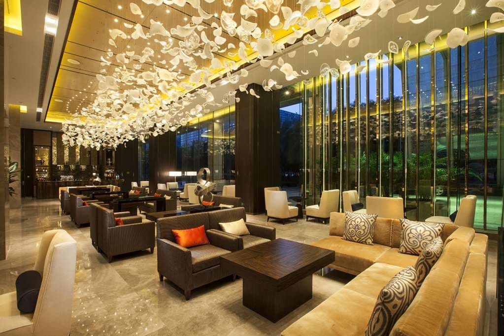 A low-angle shot of the Hilton Shenzhen Futian outdoor pool surrounded by illuminated skyscrapers at twilight.
