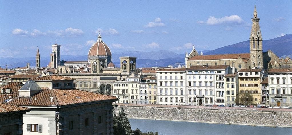 Golden hour at Plaza Hotel Lucchesi's Empireo rooftop pool, featuring a skyline view of the Florence Duomo and Santa Croce Basilica.