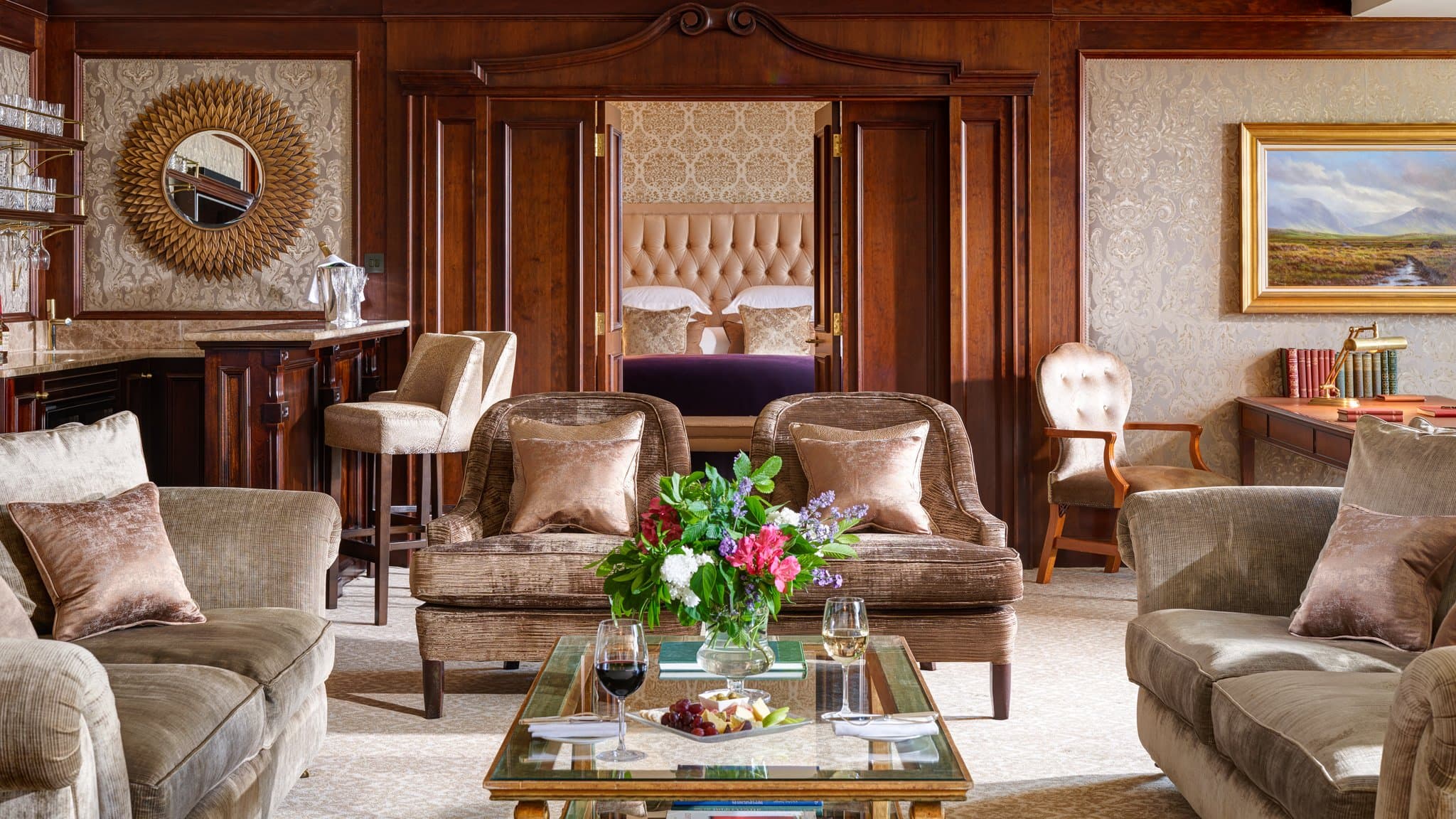 InterContinental Dublin lobby lounge featuring navy velvet armchairs, crystal chandeliers, and large windows overlooking a manicured garden courtyard.