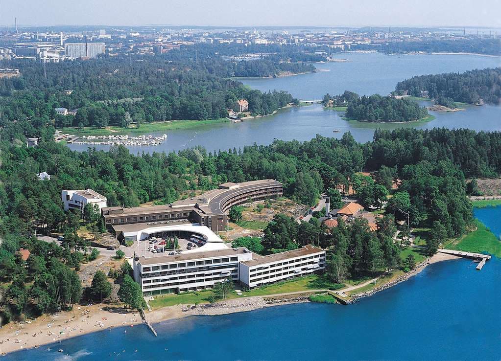 View of Hilton Helsinki Kalastajatorppa's round restaurant building with large windows overlooking the Baltic Sea at sunset.