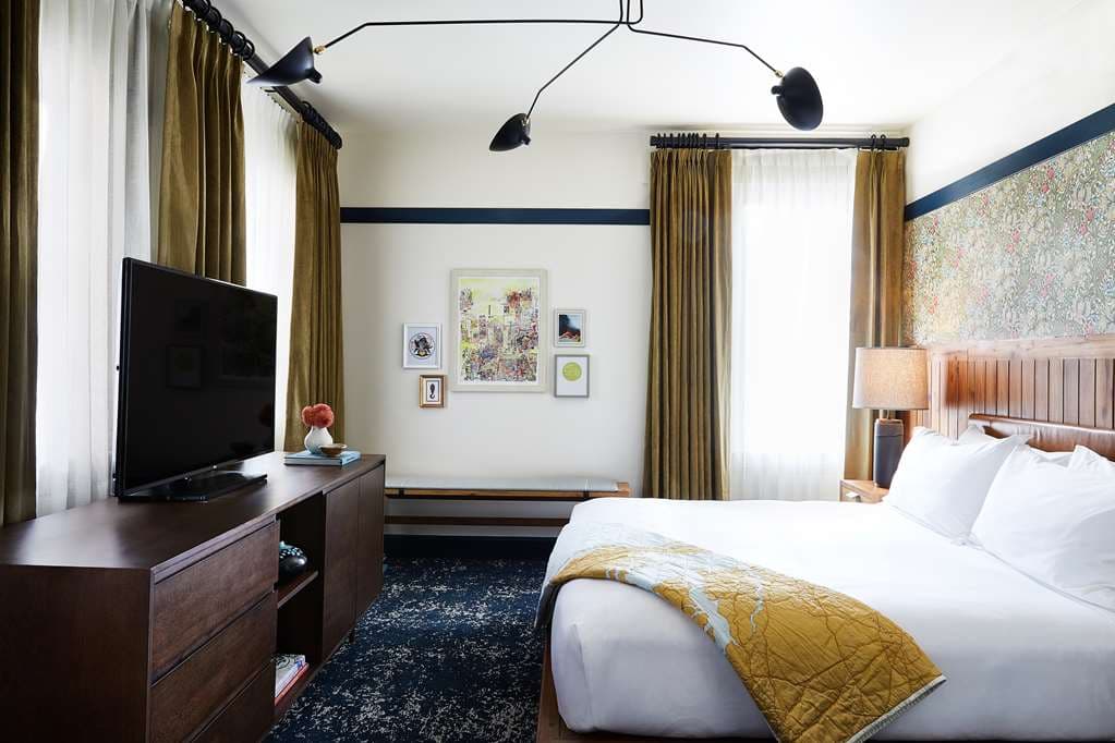 A lush, plant-filled rooftop garden room at Hotel Revival Baltimore with views of the Washington Monument.