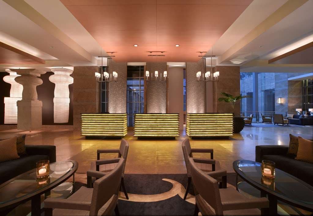 A dramatic, high-ceilinged hotel lobby featuring a monumental Lord Shiva sculpture and contemporary Indian art installations.