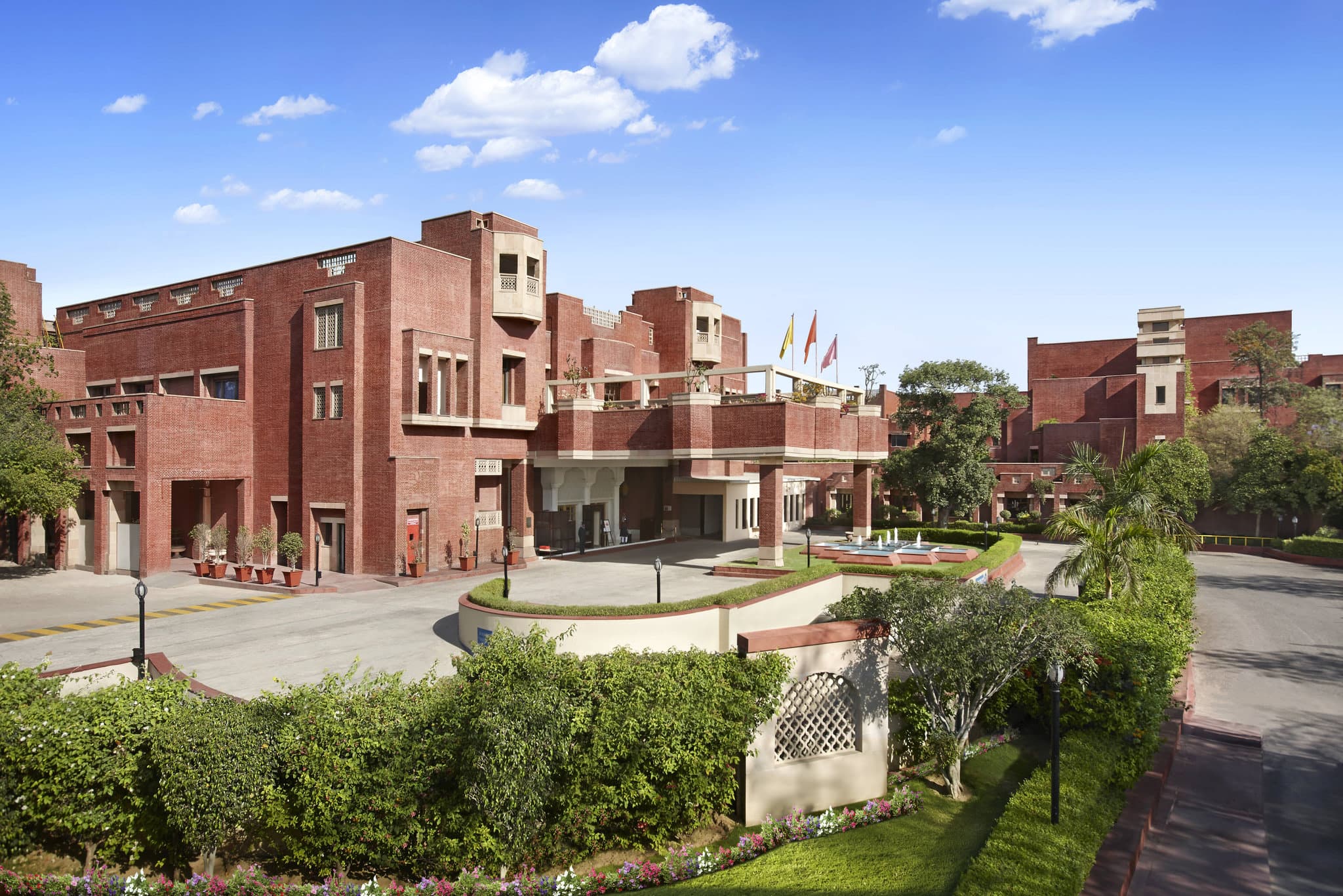A serene central courtyard at ITC Rajputana Jaipur featuring red brick architecture and a reflective pool.