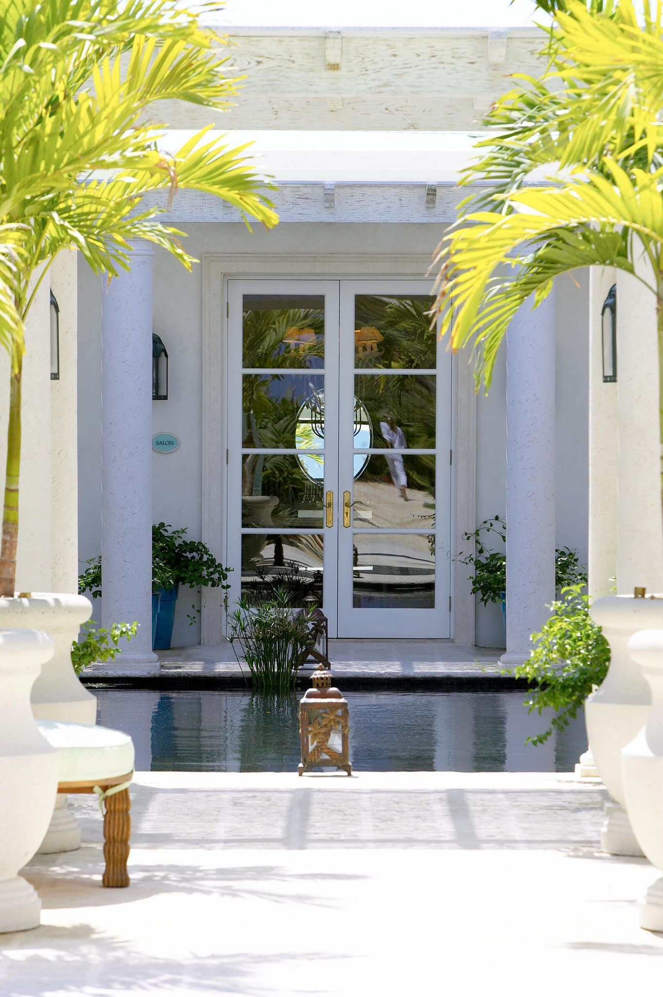 The serpentine infinity pool at The Palms Turks and Caicos curving towards Grace Bay Beach, framed by white parasols and manicured gardens.