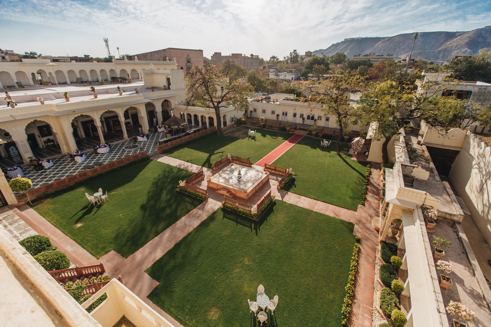 A lavish dining hall with crystal chandeliers and a long table set with silver and gold tableware at The Raj Palace.