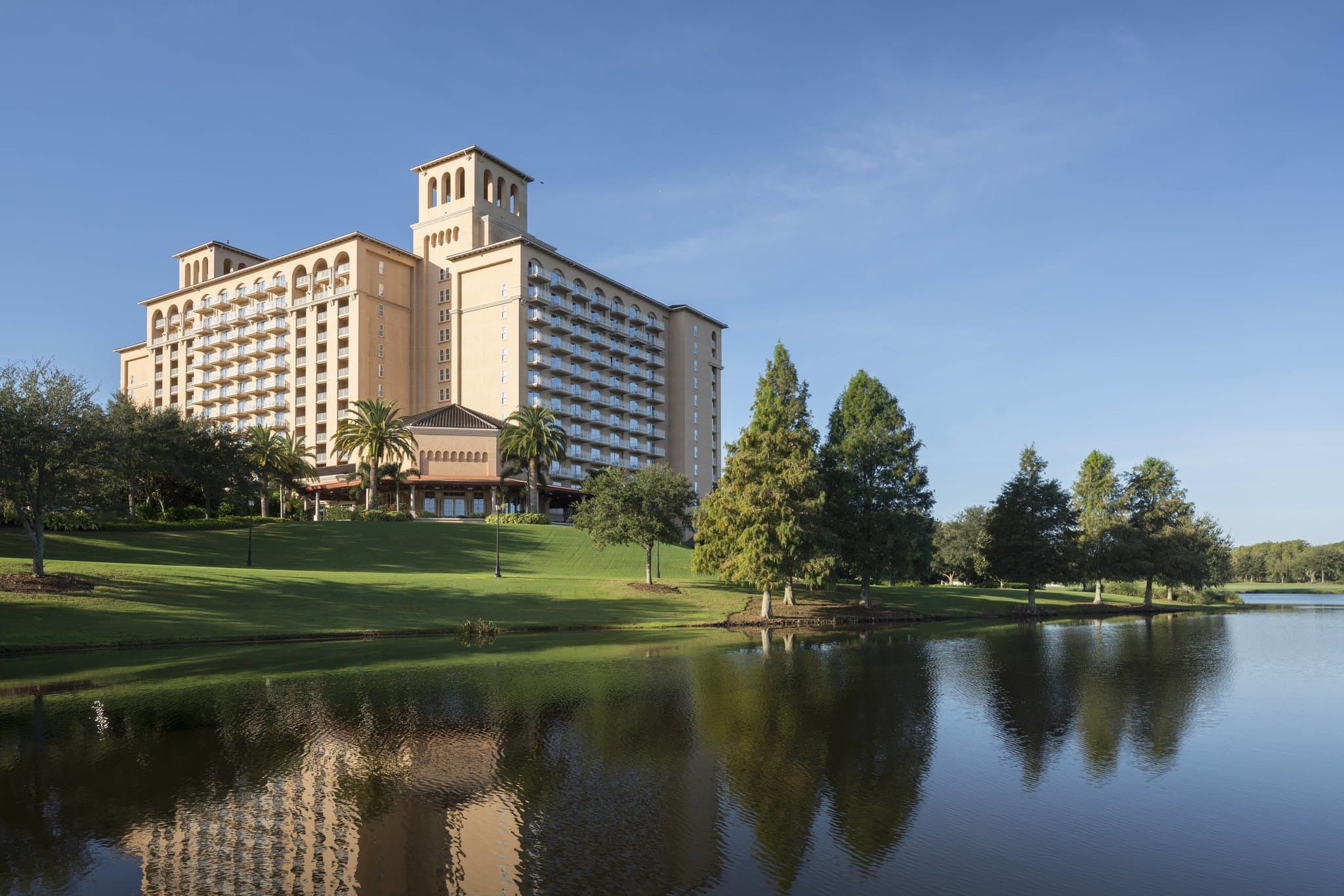 The Ritz-Carlton Orlando Grande Lakes exterior at dusk, overlooking the pool and lake with grand Italianate architecture.
