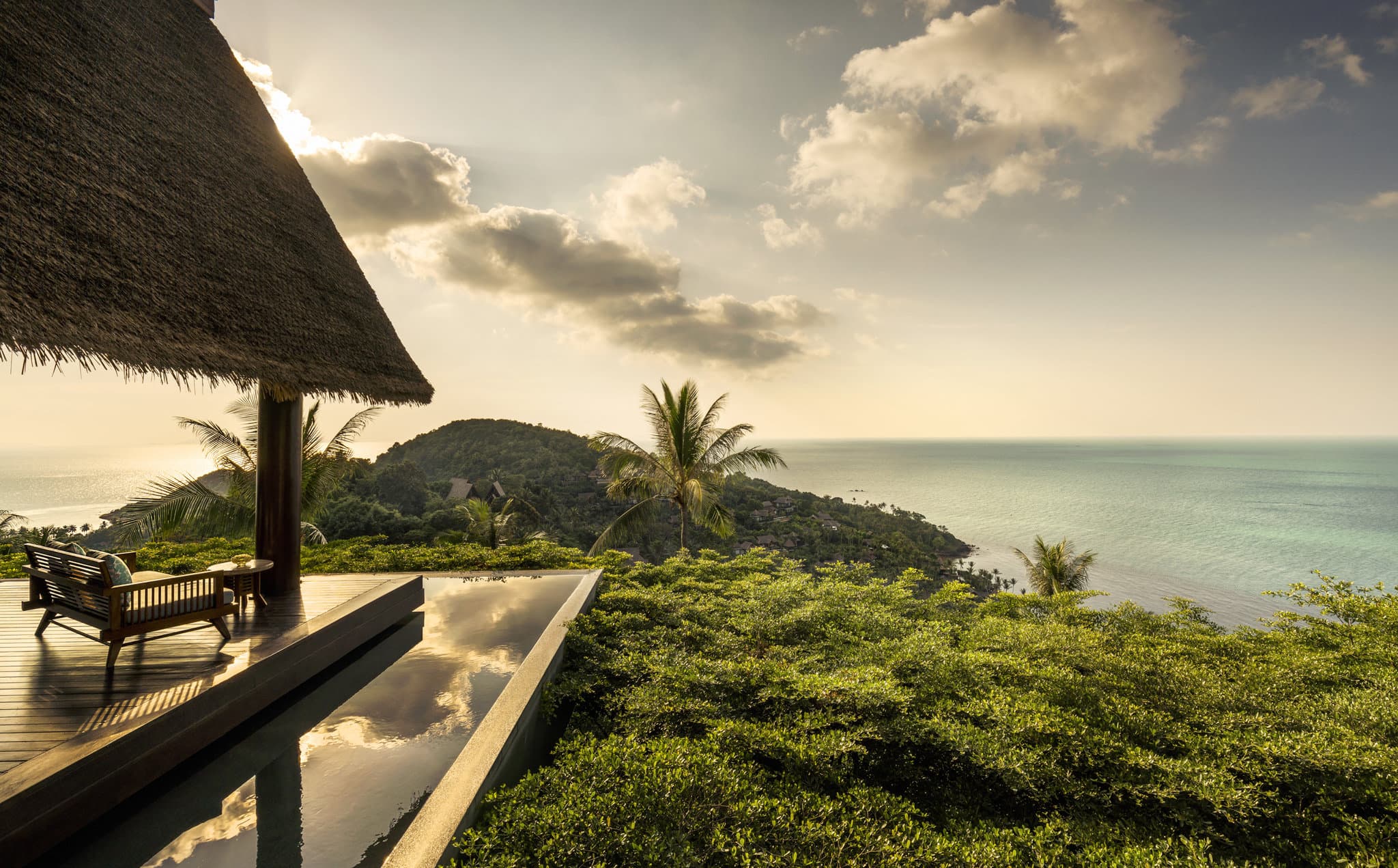 A private infinity pool at Four Seasons Koh Samui overlooking the Gulf of Thailand, framed by coconut palms and Bill Bensley's lush landscaping.