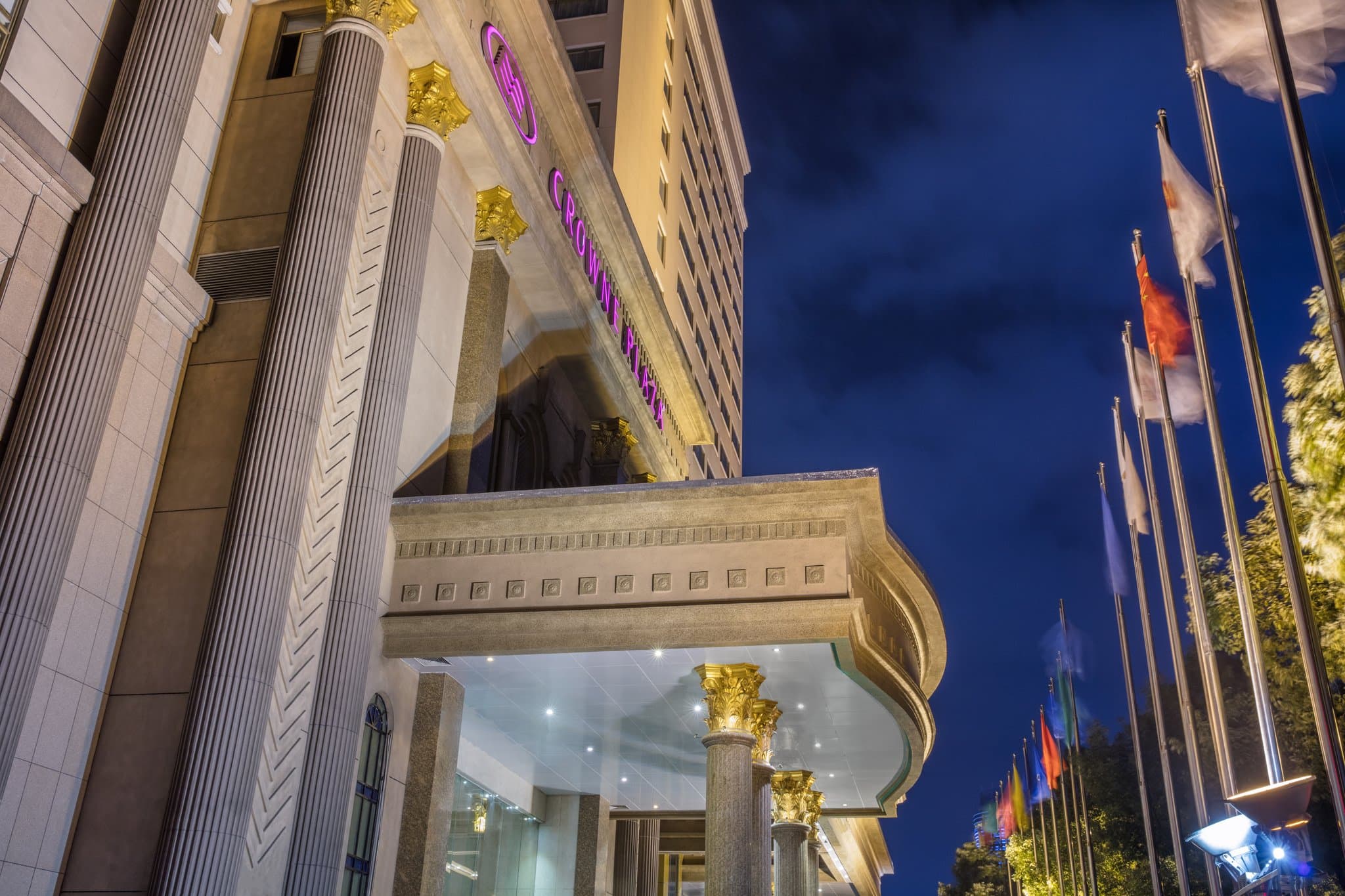 A high-angle view of the Crowne Plaza City Center Ningbo at twilight, with the illuminated Tianfeng Tower visible in the distance and the bustling Tianyi Square below.