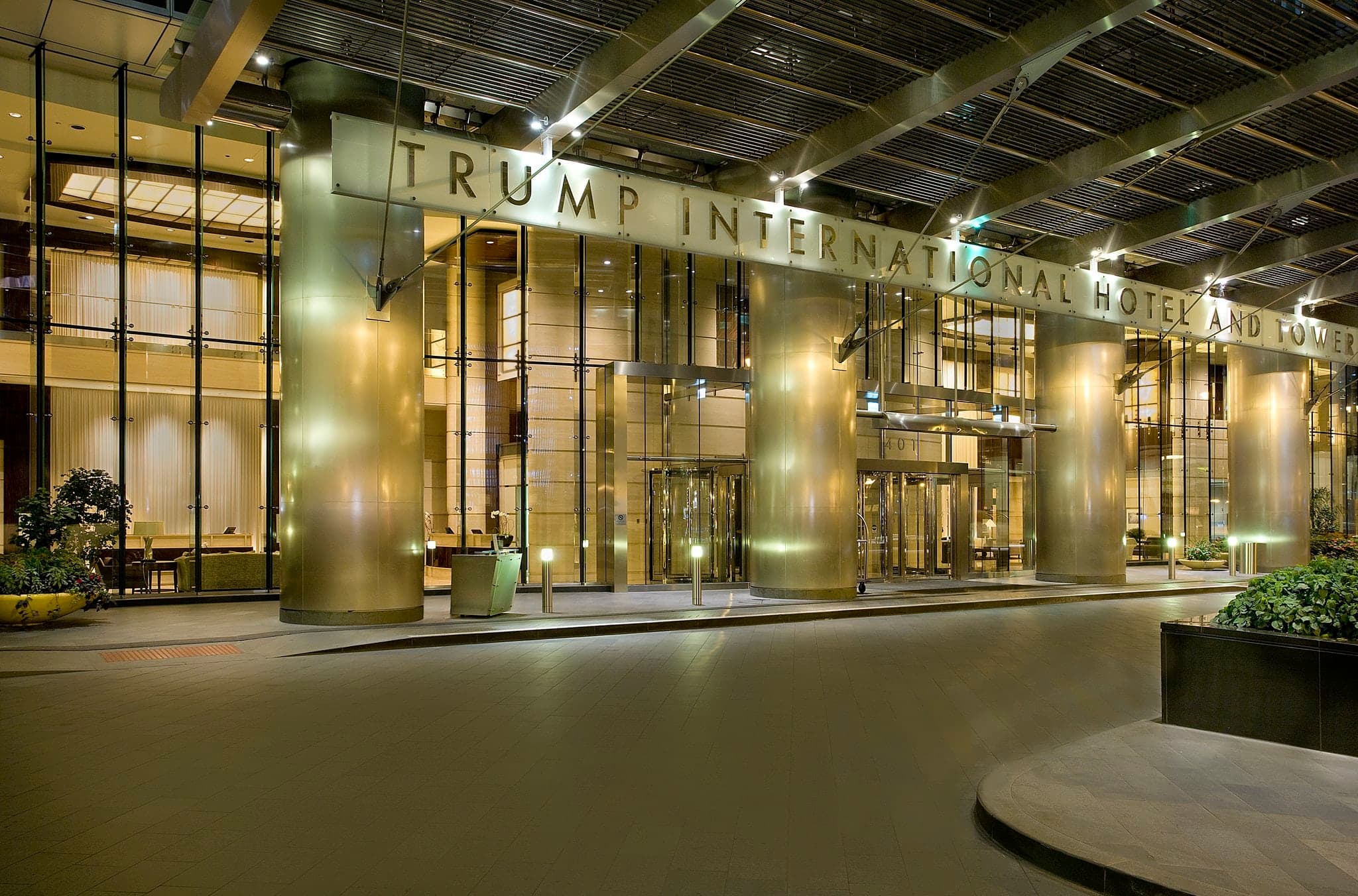 A dramatic low-angle shot of the Trump International Hotel Chicago's steel and glass façade reflecting the Chicago River at twilight.