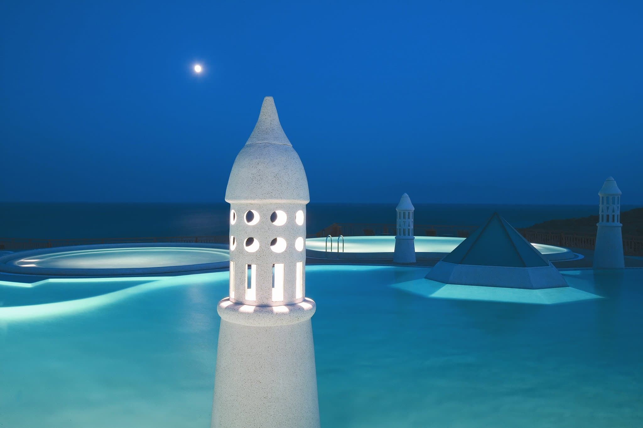 A panoramic view of the Kempinski Hotel Barbaros Bay infinity pool blending seamlessly into the deep blue Aegean Sea at sunset.