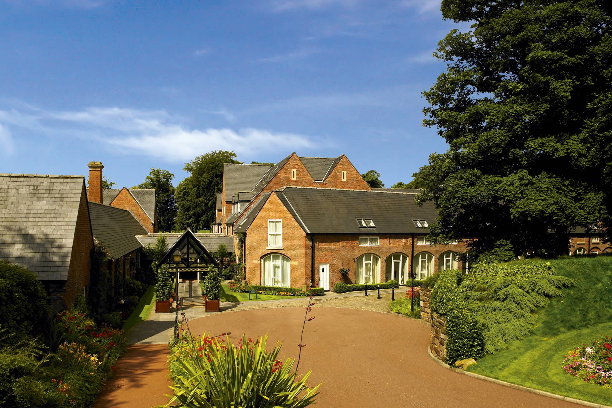 Victorian red-brick facade of Worsley Park Country Club with a fountain in the central courtyard.