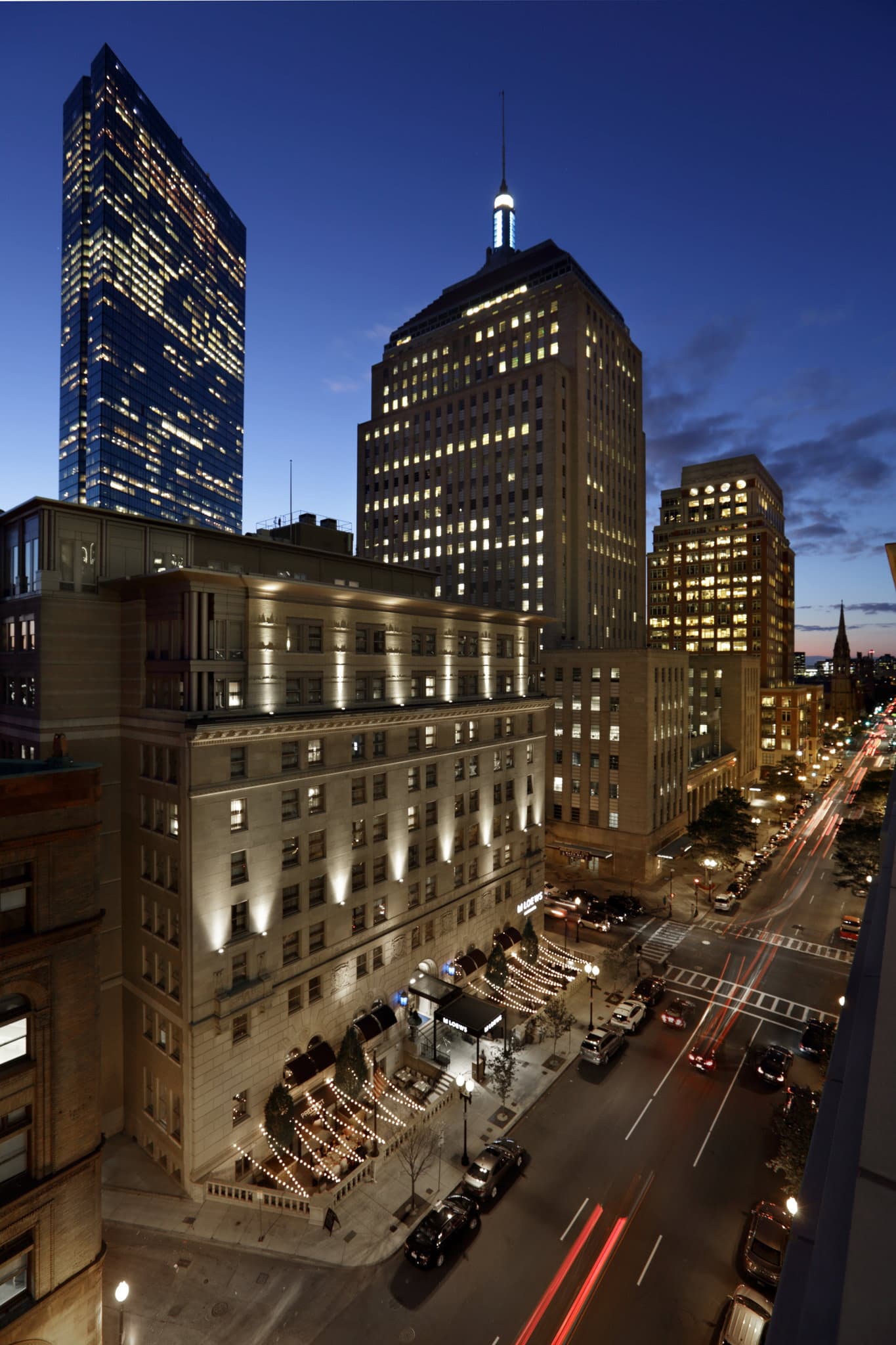 Hotel AKA Back Bay exterior showing the historic 1925 limestone police headquarters facade with modern blue awnings.