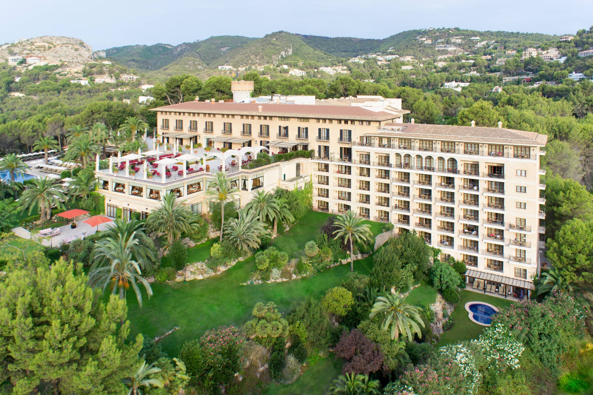 夕暮れ時のパルマ湾を見下ろす、松の木に縁取られたCastillo Hotel Son Vidaの中世の石造りの塔。