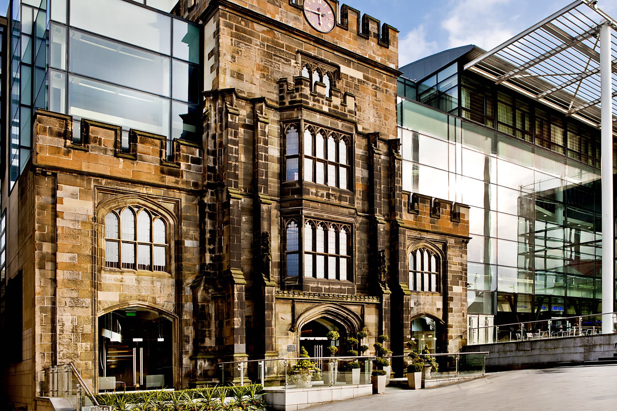A jagged glass hotel structure rising behind a historic stone church facade in Edinburgh, contrasting old and new architecture.