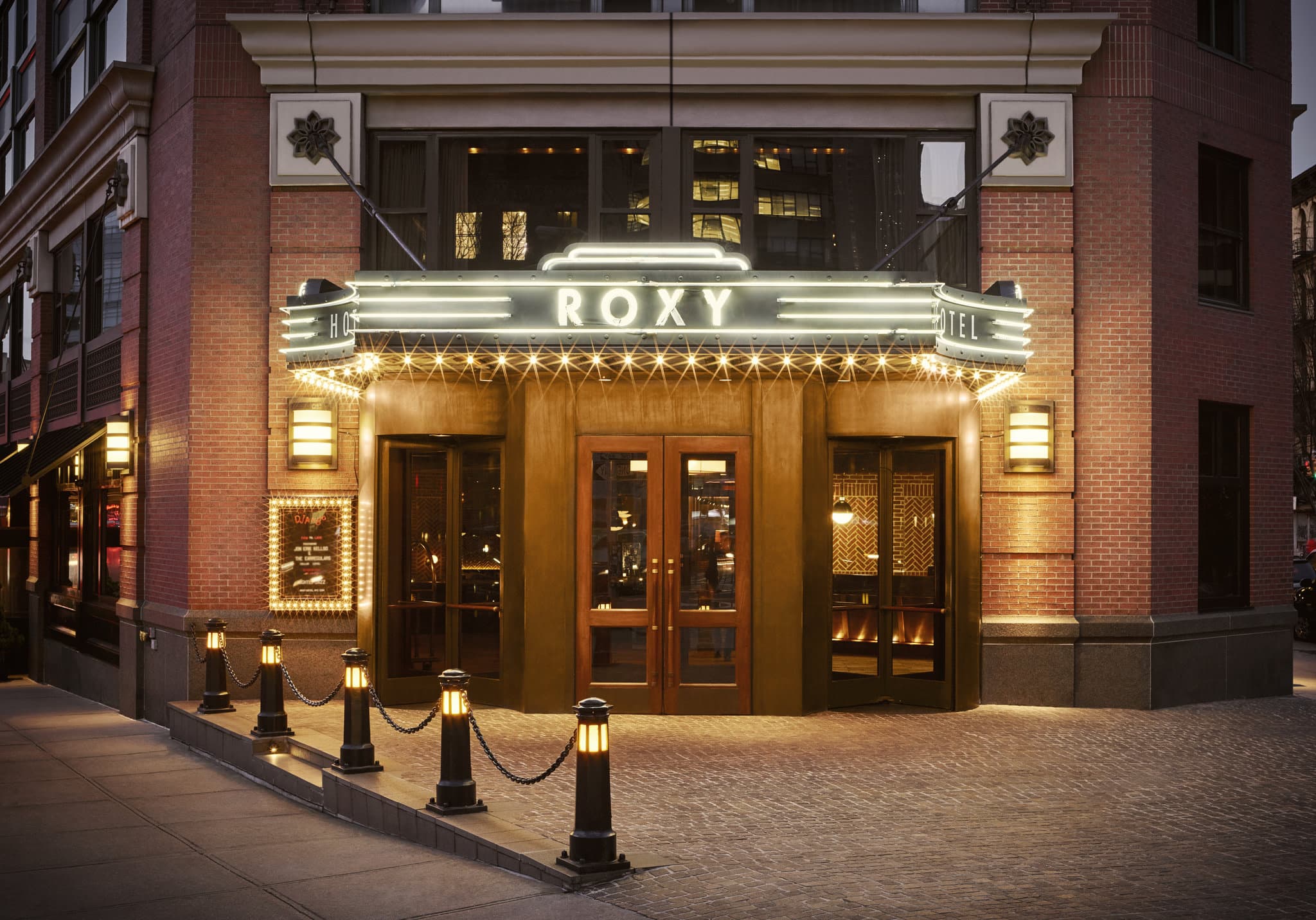 レンガの壁とベルベットの家具が特徴的な、The Roxy Hotelの賑やかな8階吹き抜けアトリウムロビーを上層階から見下ろした様子。